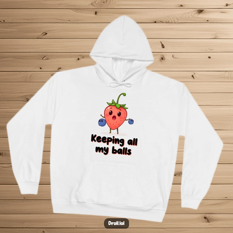 Funny hoodie showcasing a surprised strawberry juggling tiny blueberries with great energy, perfect for cozy, humorous moments.
